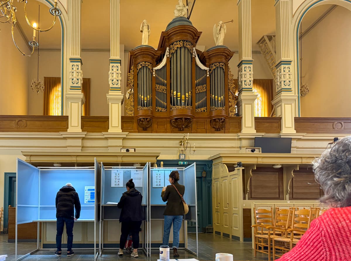 Mensen aan het stemmen in stemhokjes van stembureau Plantagekerk