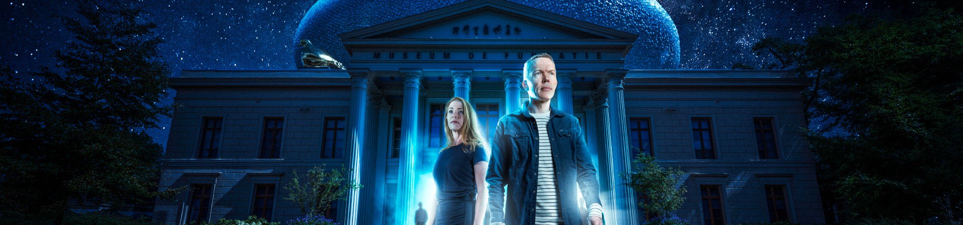 Twee collega's staan voor Museum de Fundatie in een blauw licht.