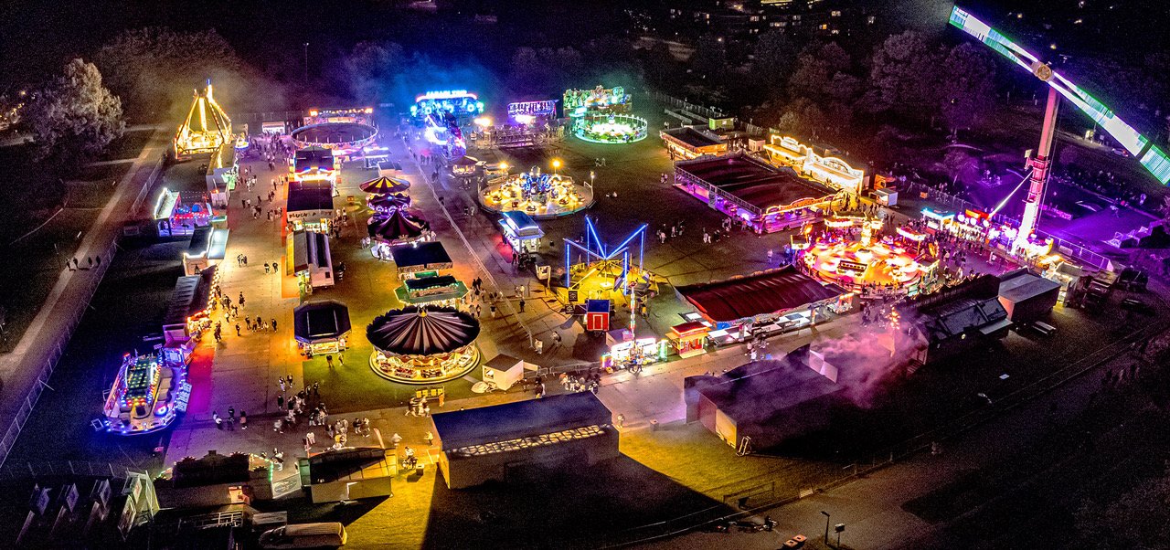 Sfeervolle avondfoto van het terrein van de Zomerkermis in Park de Wezenlanden. De foto is met een drone gemaakt.