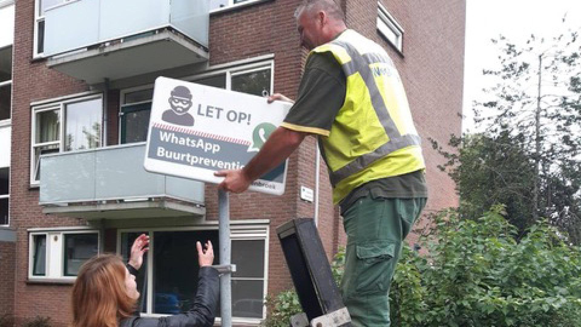 Een inwoner plaatst een bord voor een buurtpreventie-app